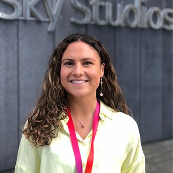 Portrait photo of Anna smiling into the camera, outside the Sky studios